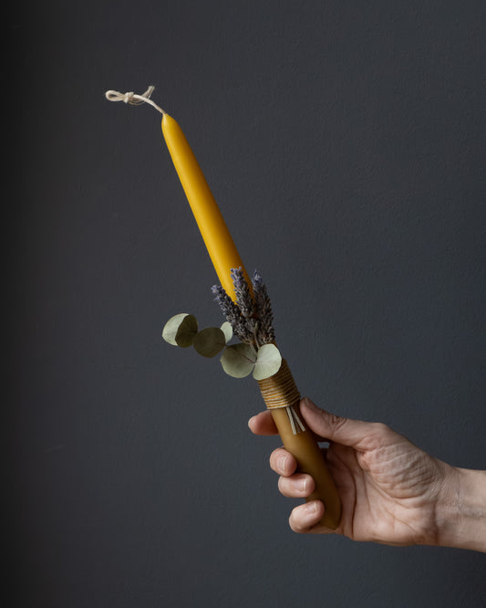 Hand holding a beeswax candle with eucalyptus and lavender