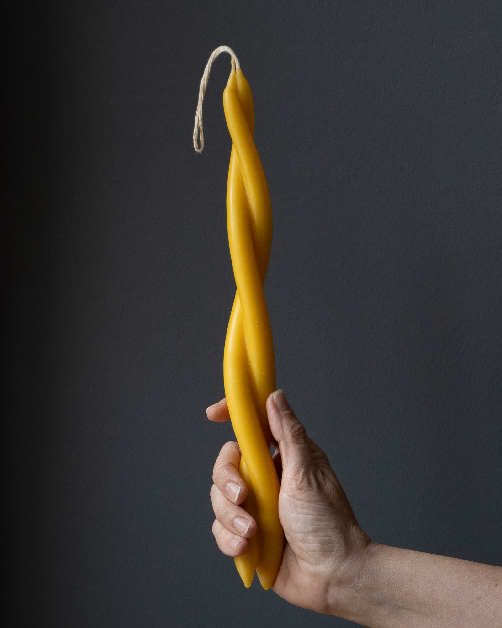 Hand holding a twisted beeswax candle
