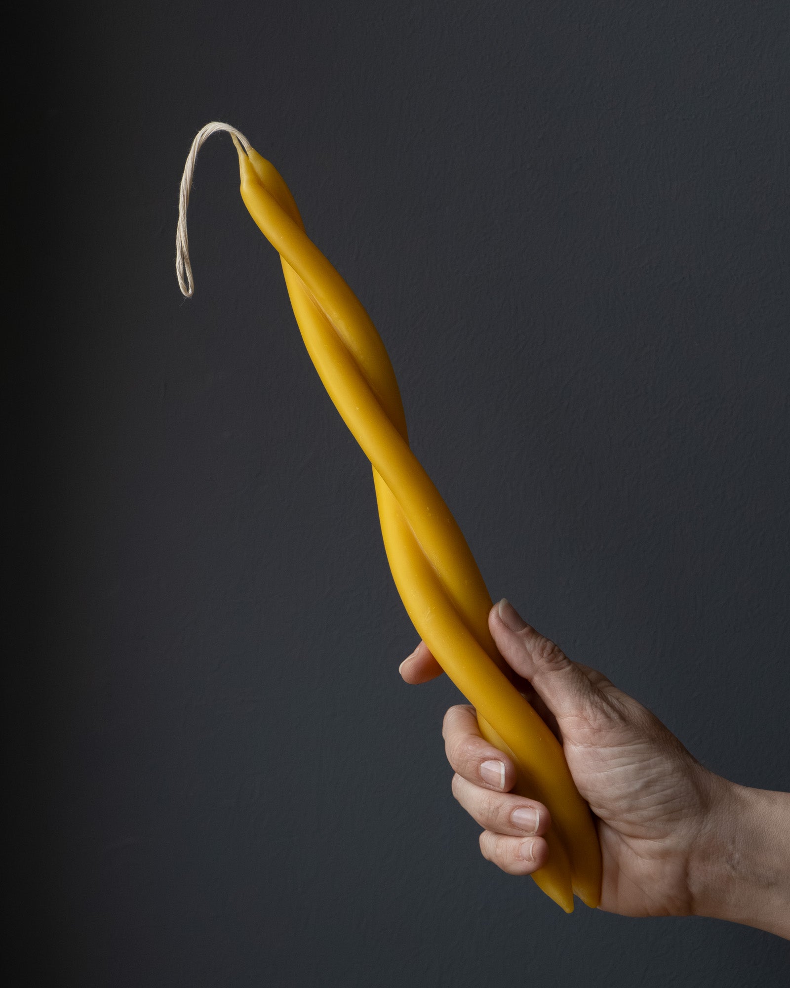 Hand holding a twisted beeswax candle