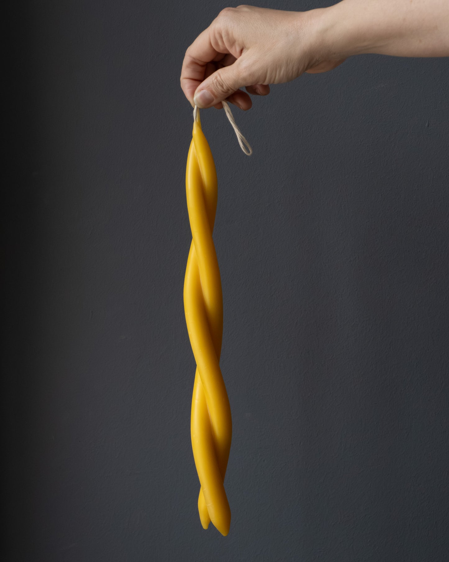 Hand holding a twisted beeswax candle