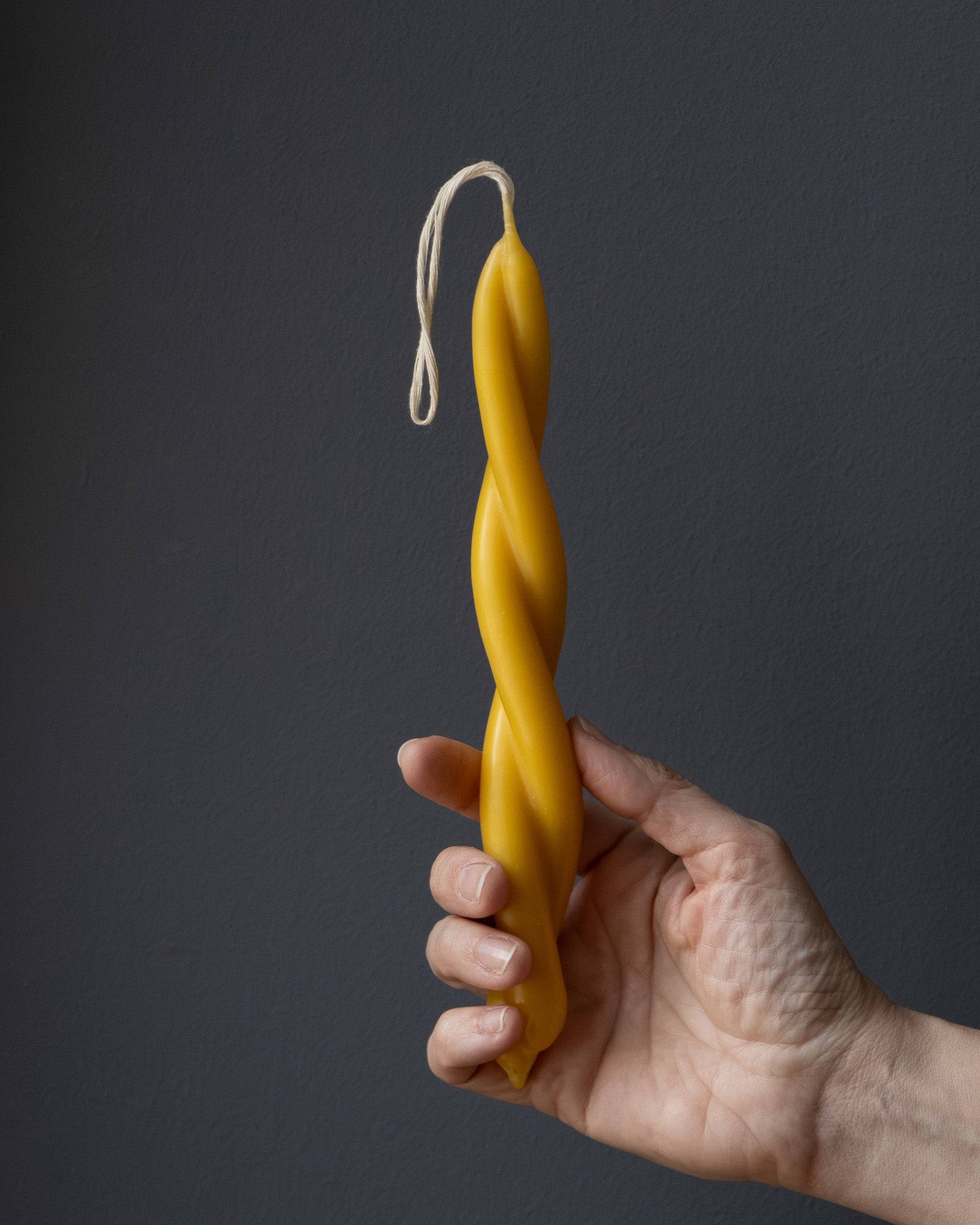 Hand holding a small twisted beeswax candle