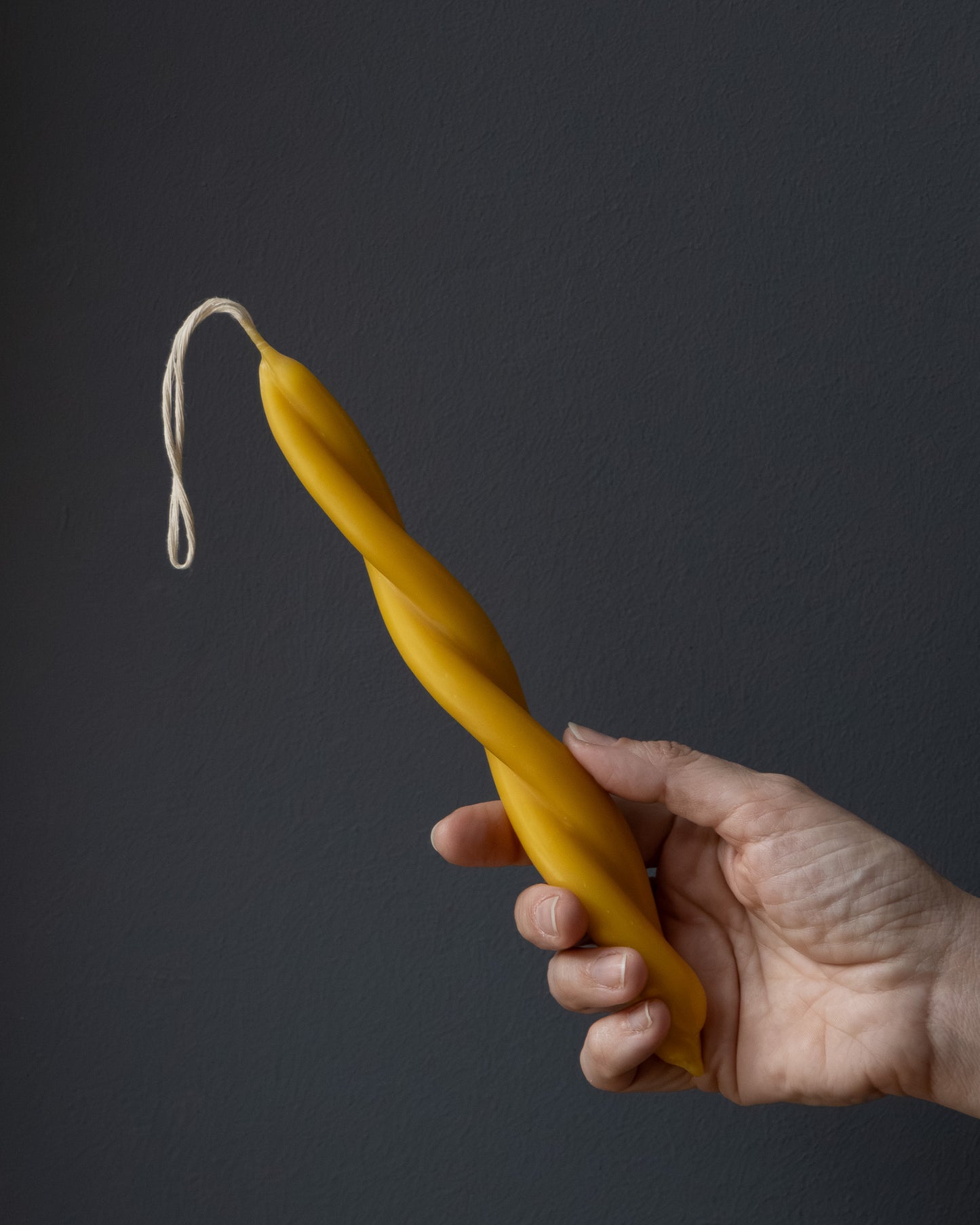 Hand holding a small twisted beeswax candle