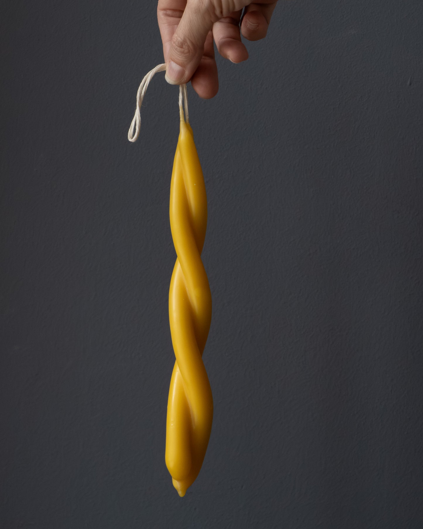 Hand holding a small twisted beeswax candle