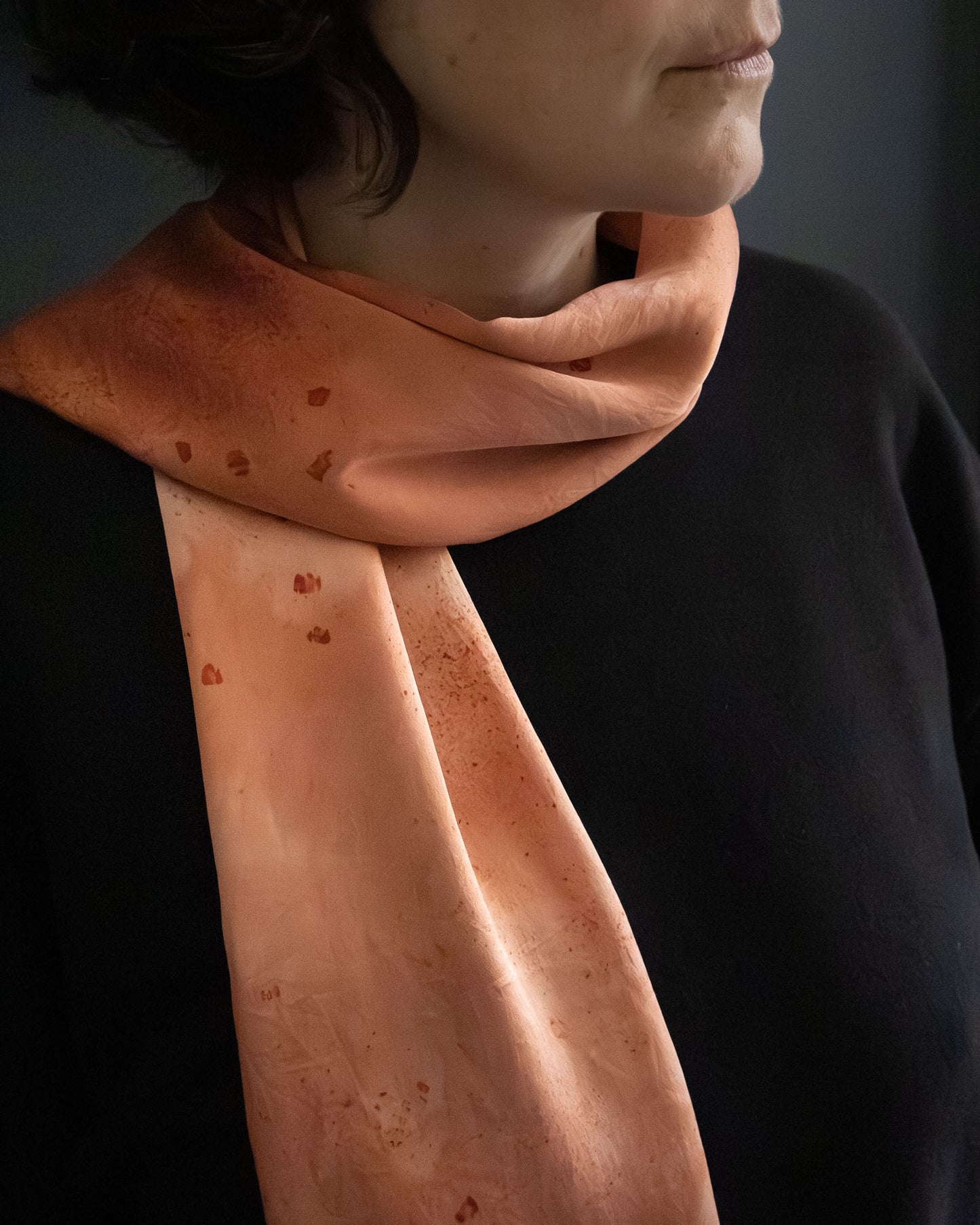 naturally dyed silk scarf in deep madder tones, worn around the neck