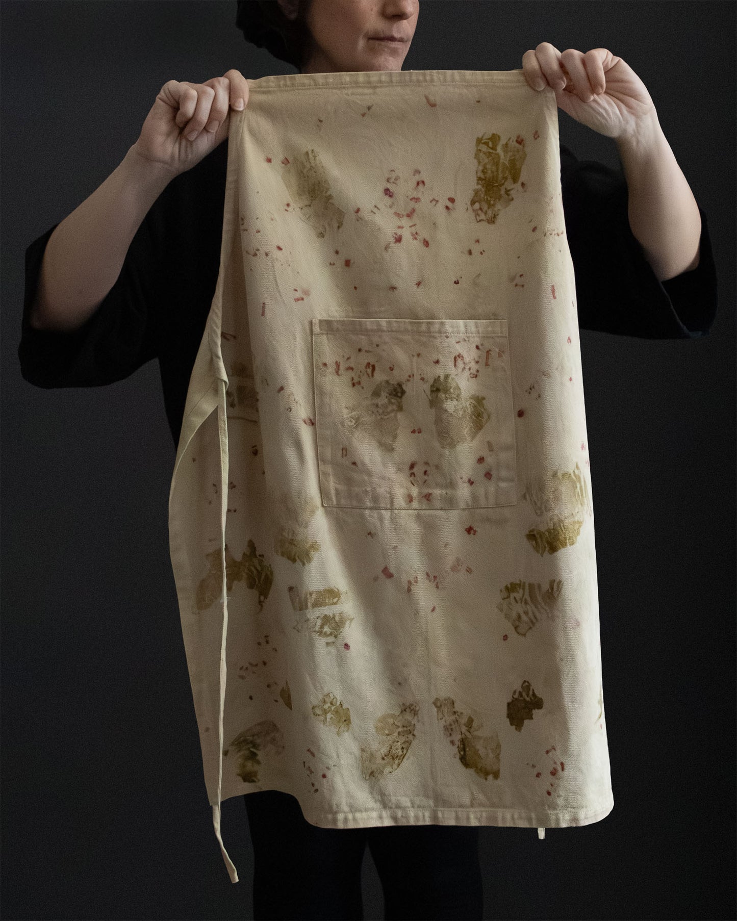 naturally dyed apron with botanical patterns, held open
