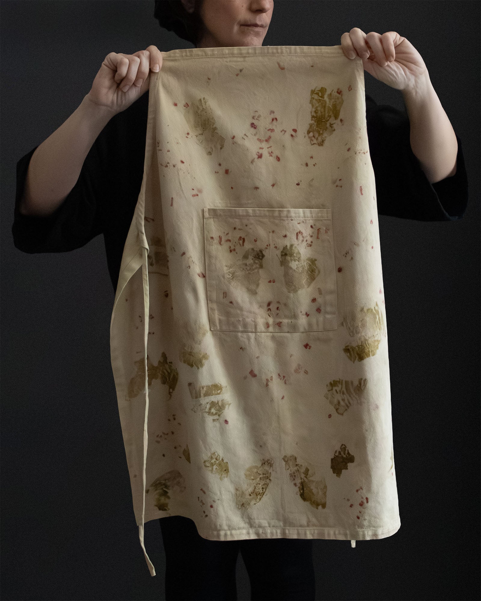naturally dyed apron with botanical patterns, held open

