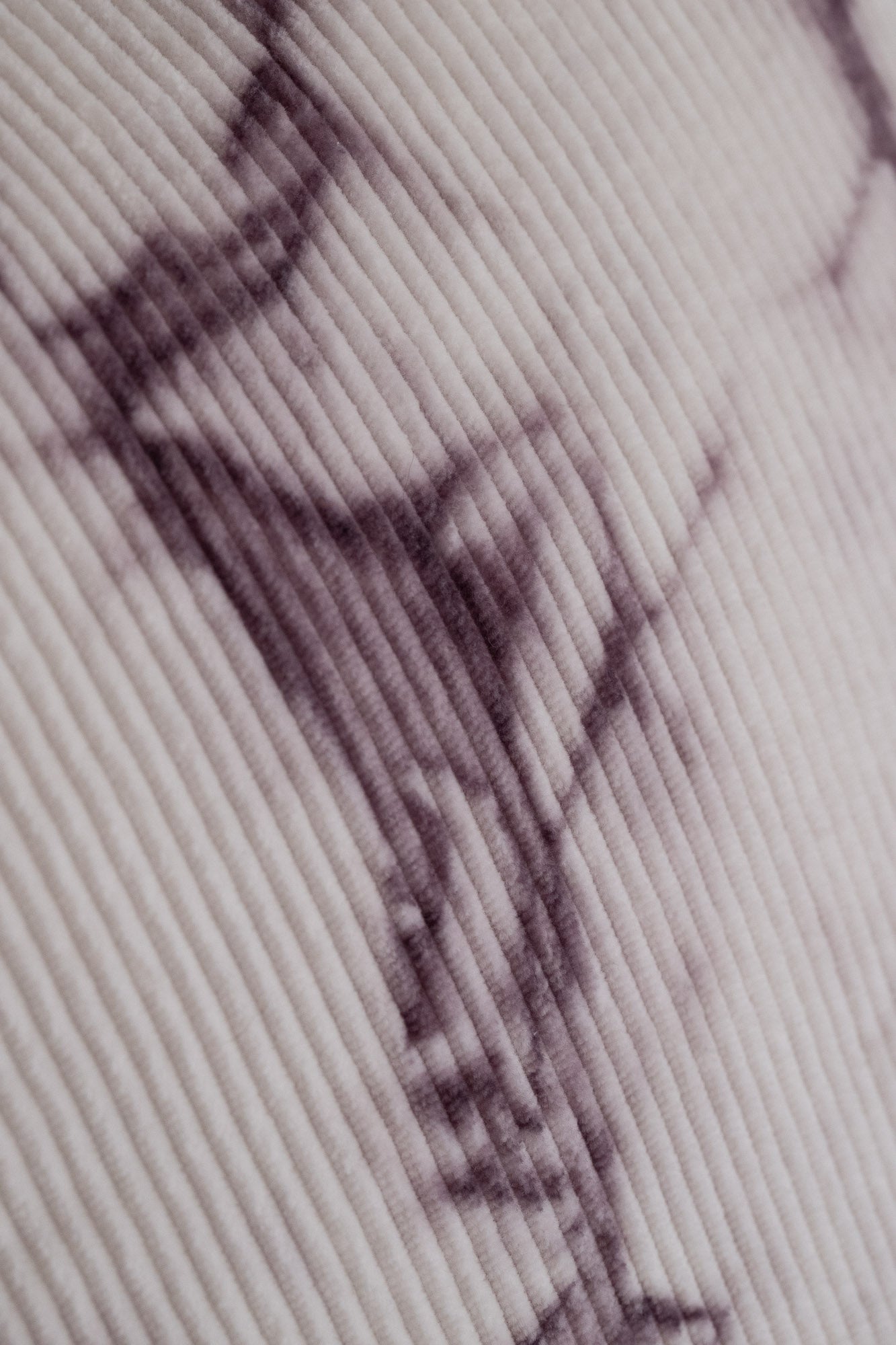 Close-up of natural logwood dye purple patterns on organic cotton corduroy cushion cover.