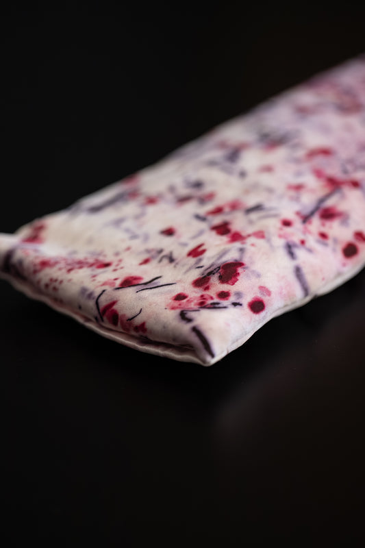 Close-up of a naturally dyed silk eye pillow with cochineal red and logwood purple imprints on Greek mulberry silk.