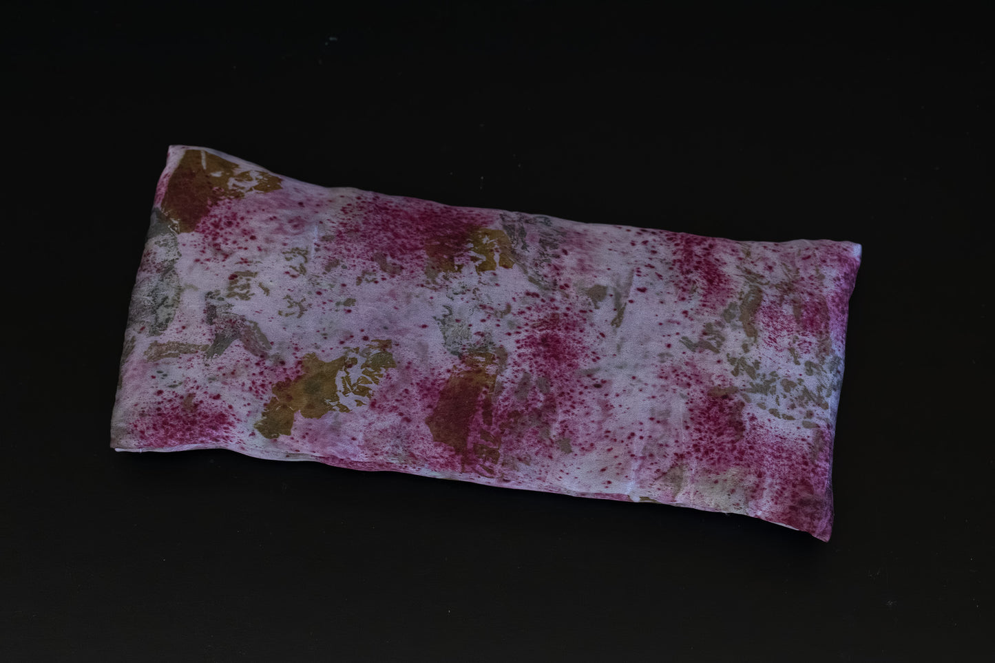 Naturally dyed silk eye pillow in full view, featuring cochineal and logwood tones with eco-print imprints from onion skins and rose petals on Greek mulberry silk.