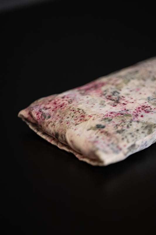 Close-up of a naturally dyed silk eye pillow with pink and soft green colour details.